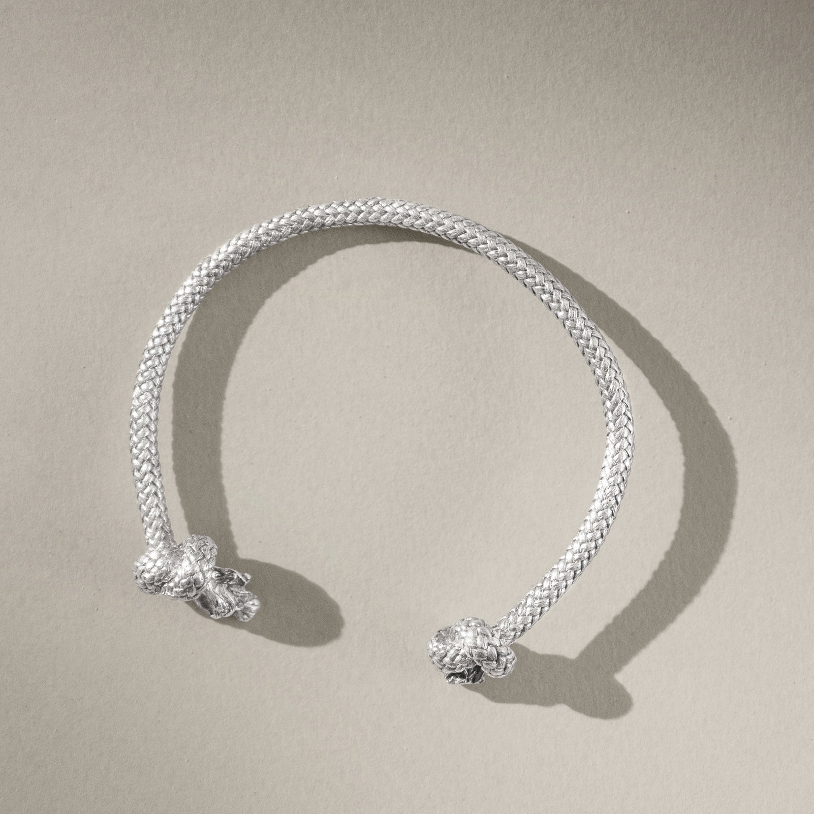 Silver bracelet with two decorative elements on a beige background